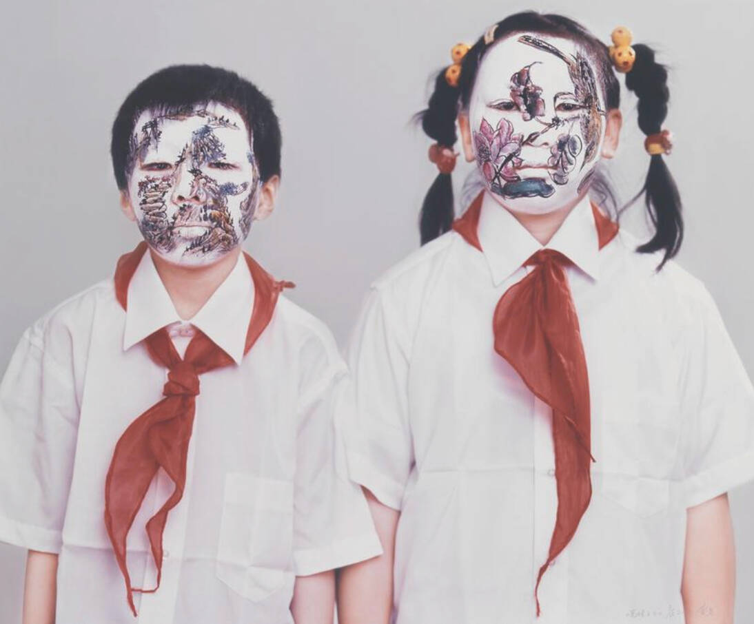 A chromogenic print of a young boy and girl. They are both wearing white button up short sleeve shirts and red scarves. The boy's face is painted white with a mountain scene. The girl on the right has her face painted with a white base and pink colored fl
